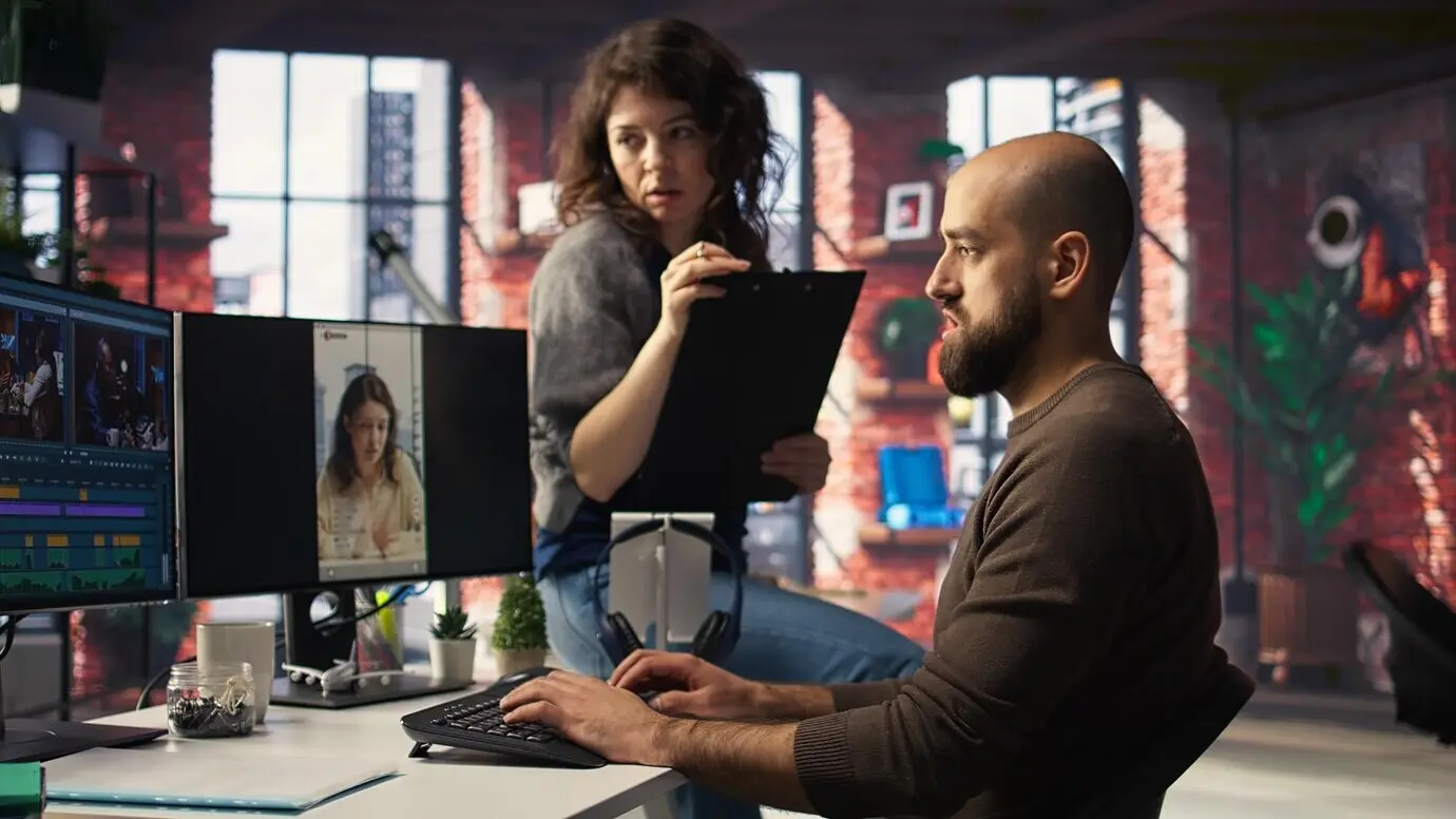 Ein Team bespricht die Content-Strategie und Trends, während es an Computern Videomaterial sichtet.